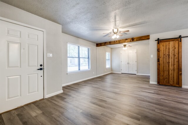 entryway featuring a barn door, baseboards, a textured ceiling, and wood finished floors