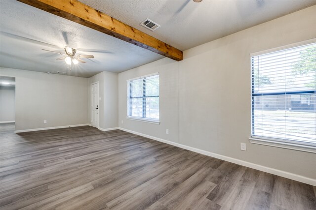 unfurnished room featuring a ceiling fan, baseboards, visible vents, beam ceiling, and a textured ceiling