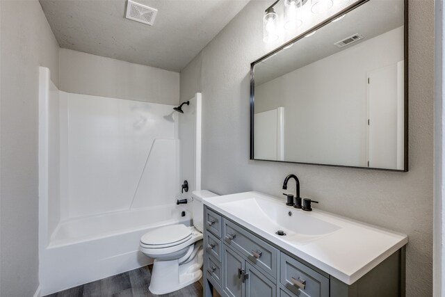 full bathroom with vanity, wood finished floors, visible vents, bathtub / shower combination, and toilet