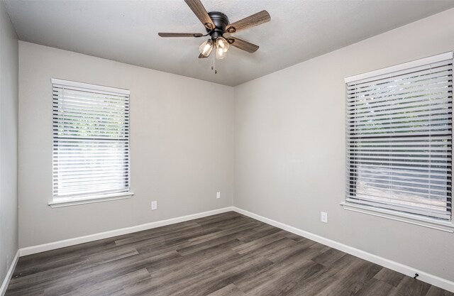 spare room with baseboards, dark wood-type flooring, and a ceiling fan