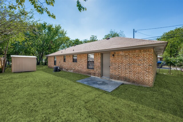 rear view of property with brick siding, a shed, central AC, a lawn, and an outbuilding