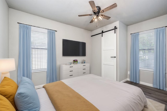 bedroom with ceiling fan, a barn door, baseboards, and wood finished floors