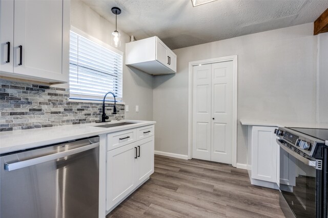 kitchen with electric range, light wood-style flooring, a sink, white cabinetry, and dishwasher