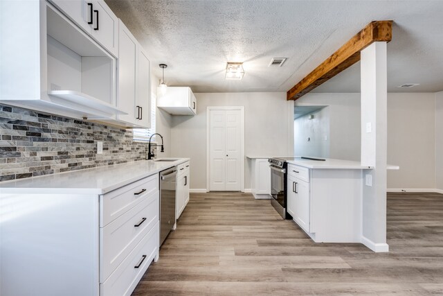 kitchen featuring a sink, light wood-style floors, appliances with stainless steel finishes, a textured ceiling, and tasteful backsplash