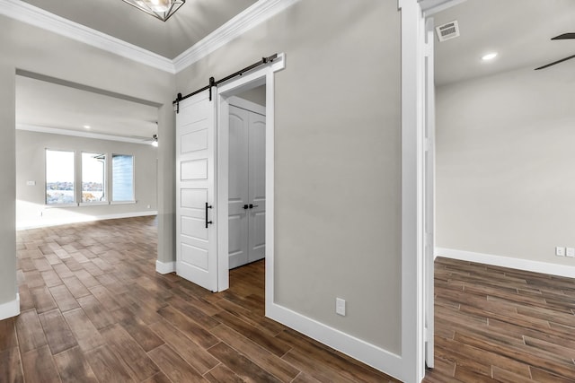 corridor featuring a barn door, dark hardwood / wood-style floors, and ornamental molding