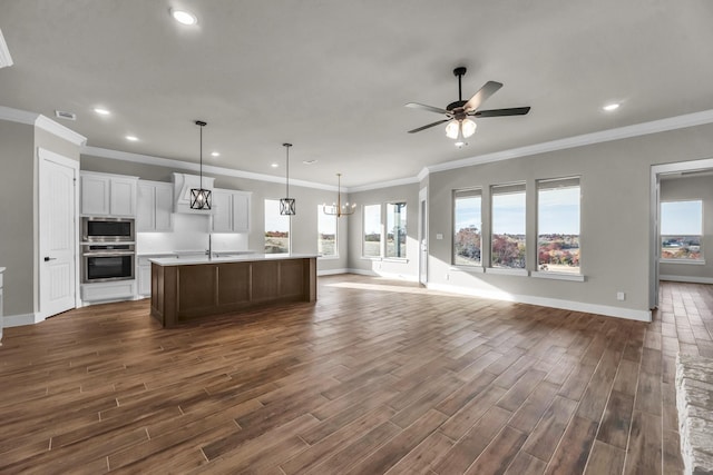 kitchen featuring ceiling fan with notable chandelier, stainless steel appliances, decorative light fixtures, a center island with sink, and dark hardwood / wood-style floors