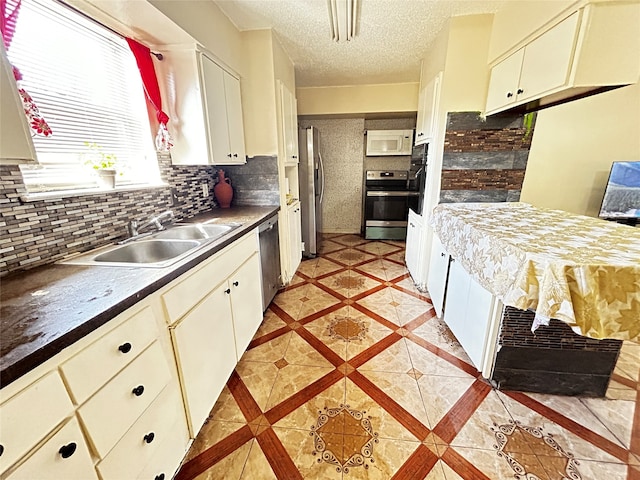 kitchen featuring white cabinets, sink, tasteful backsplash, a textured ceiling, and stainless steel appliances