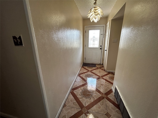 doorway with a textured ceiling and light tile patterned flooring