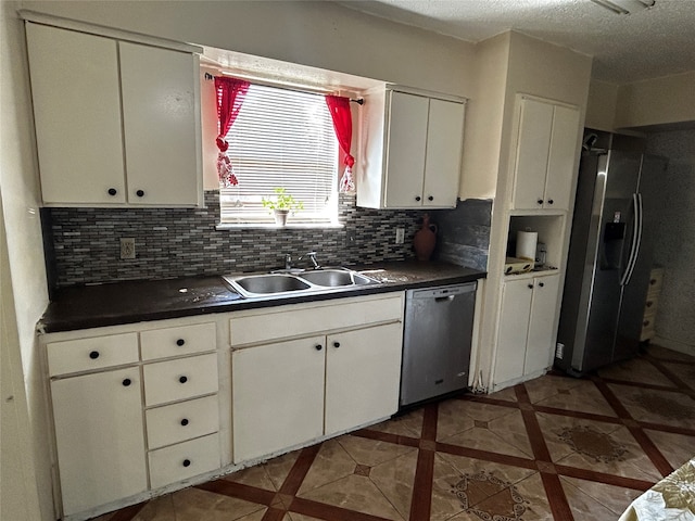 kitchen with white cabinets, sink, a textured ceiling, appliances with stainless steel finishes, and decorative backsplash