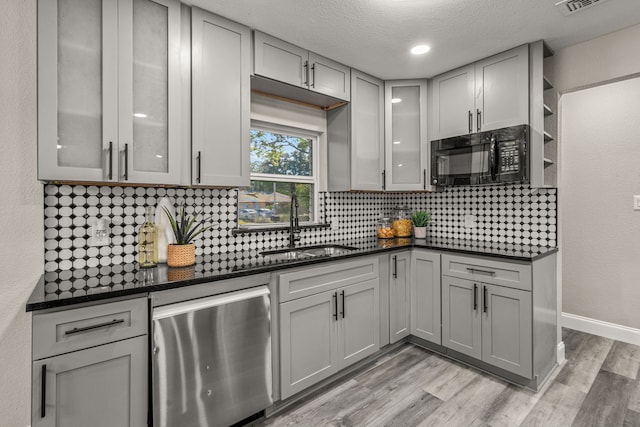 kitchen featuring decorative backsplash, dishwasher, light hardwood / wood-style floors, and gray cabinetry