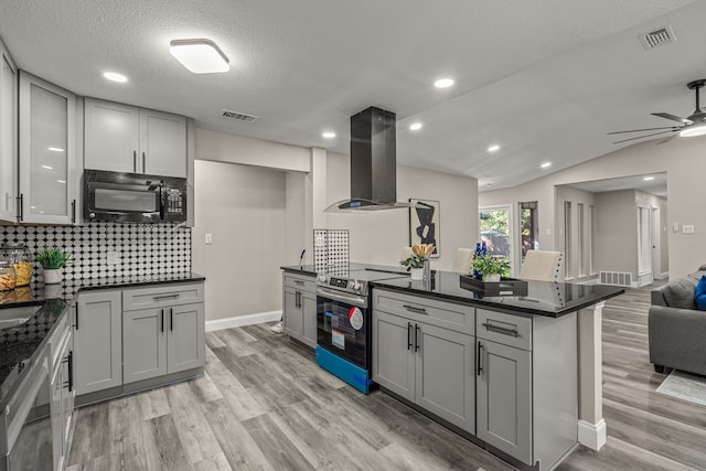 kitchen featuring island exhaust hood, stainless steel appliances, vaulted ceiling, and gray cabinetry