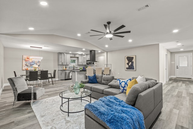 living room with light hardwood / wood-style flooring, lofted ceiling, and ceiling fan