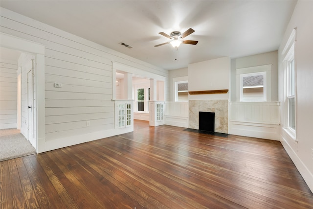 unfurnished living room featuring wood walls, dark hardwood / wood-style floors, and ceiling fan