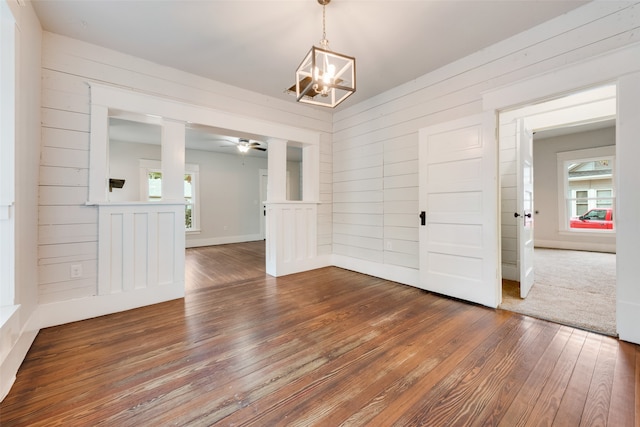 unfurnished dining area with hardwood / wood-style floors, plenty of natural light, and wooden walls