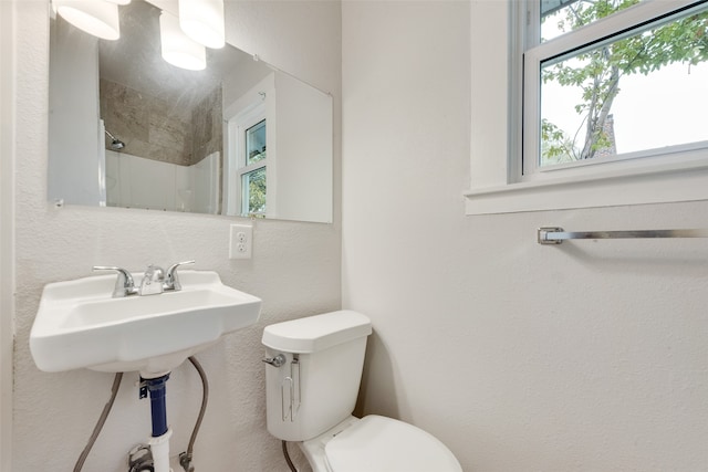 bathroom featuring sink, toilet, and tiled shower