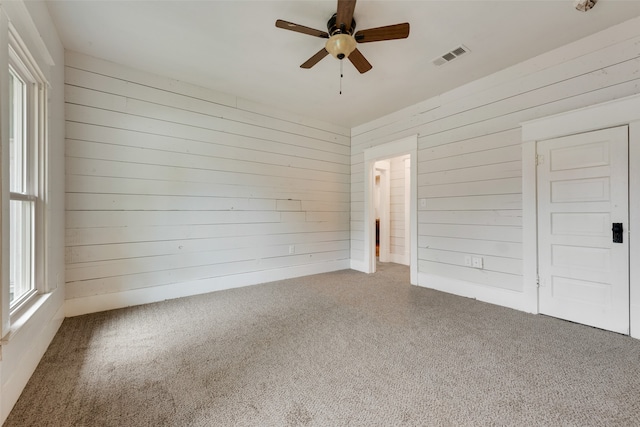 empty room featuring wood walls and ceiling fan