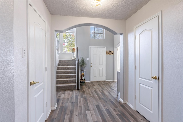 foyer entrance with a textured ceiling and dark wood-type flooring