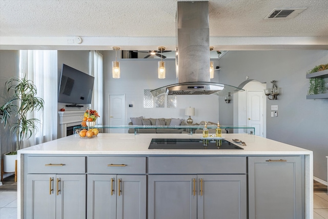 kitchen with light tile patterned floors, black electric stovetop, island exhaust hood, and a kitchen island with sink