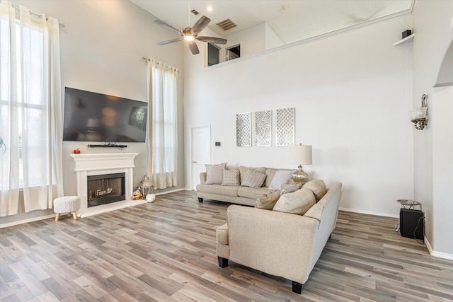 living room with a towering ceiling, ceiling fan, and plenty of natural light