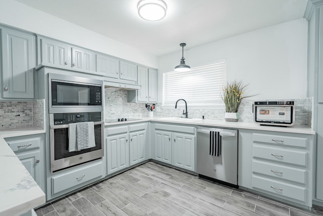 kitchen featuring decorative light fixtures, stainless steel appliances, sink, and gray cabinetry