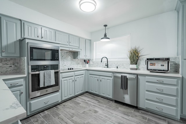 kitchen with stainless steel appliances, tasteful backsplash, sink, hanging light fixtures, and gray cabinets