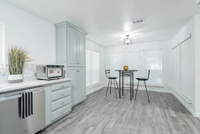 kitchen featuring stainless steel dishwasher, gray cabinets, and light wood-type flooring