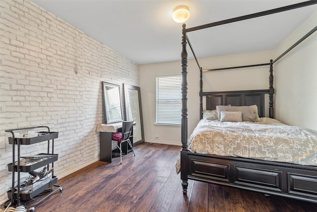 bedroom featuring brick wall and dark hardwood / wood-style flooring