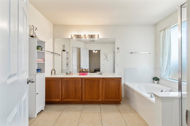 bathroom with tile patterned flooring, vanity, and a relaxing tiled tub