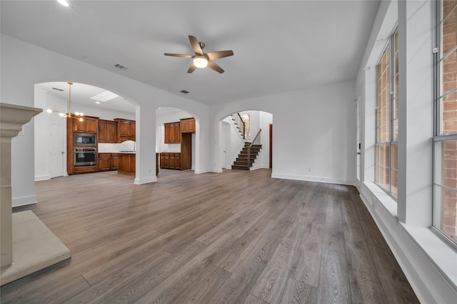 unfurnished living room featuring ceiling fan with notable chandelier and hardwood / wood-style floors