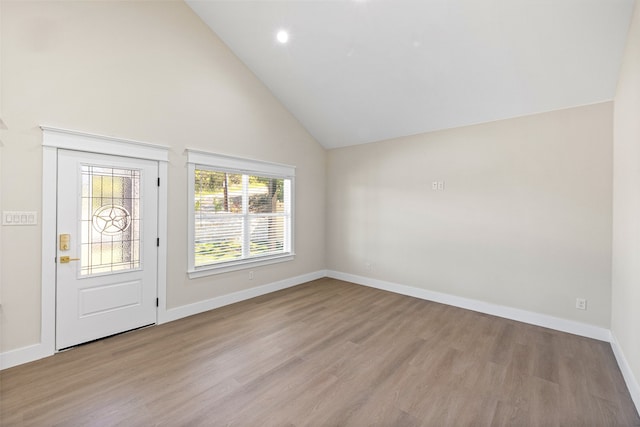 foyer with light wood-type flooring and high vaulted ceiling