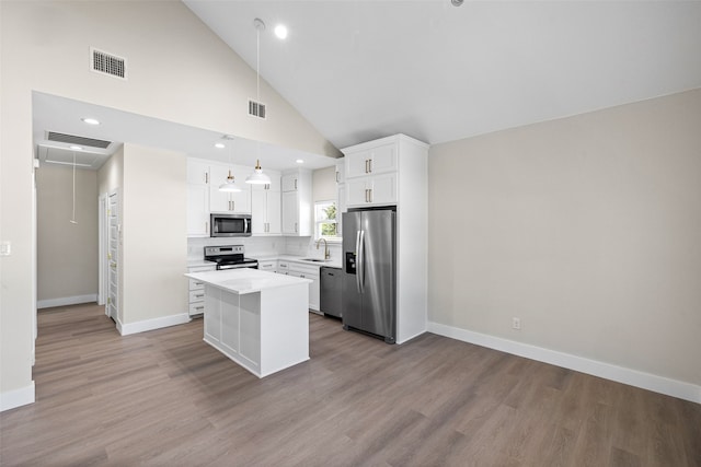 kitchen featuring appliances with stainless steel finishes, sink, white cabinets, a center island, and hanging light fixtures