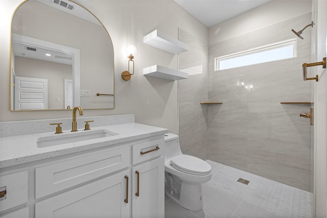 bathroom with tiled shower, vanity, and toilet