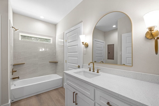 bathroom featuring hardwood / wood-style floors, vanity, electric panel, and tiled shower / bath