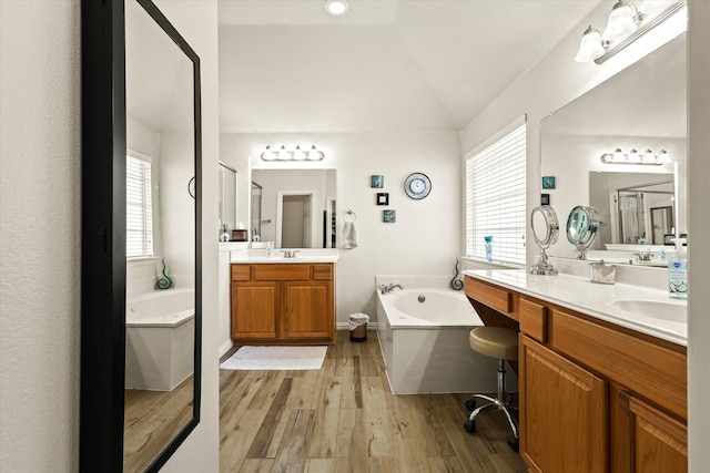 bathroom with a bathtub, lofted ceiling, hardwood / wood-style floors, and vanity