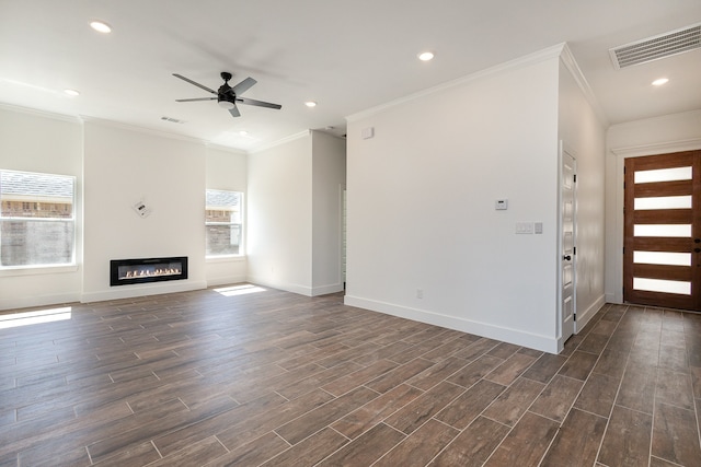 unfurnished living room with ornamental molding, a wealth of natural light, ceiling fan, and dark wood-type flooring