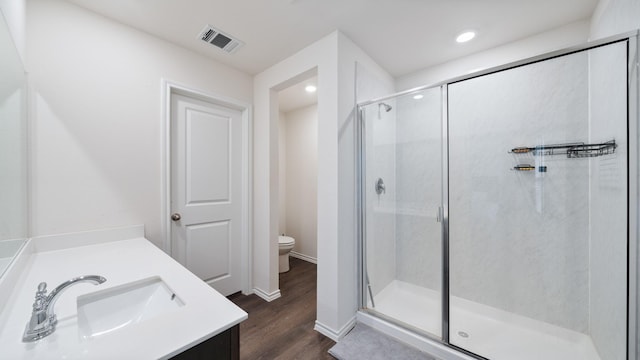 bathroom featuring hardwood / wood-style floors, toilet, vanity, and an enclosed shower