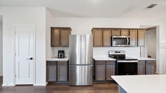 kitchen with appliances with stainless steel finishes and dark hardwood / wood-style floors