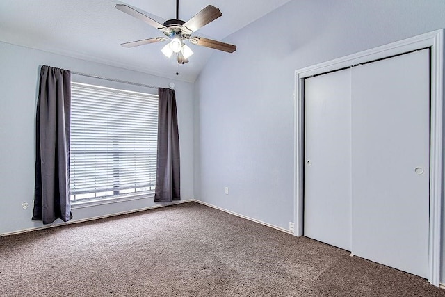 unfurnished bedroom with ceiling fan, a closet, dark carpet, and vaulted ceiling