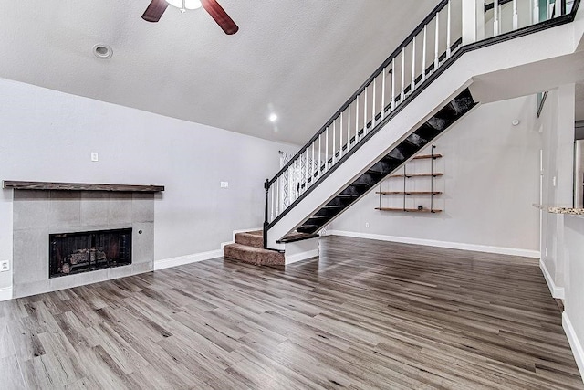 unfurnished living room featuring a fireplace, hardwood / wood-style floors, a textured ceiling, and ceiling fan