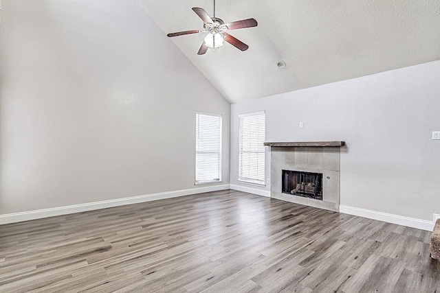 unfurnished living room with a tile fireplace, ceiling fan, light hardwood / wood-style flooring, and high vaulted ceiling