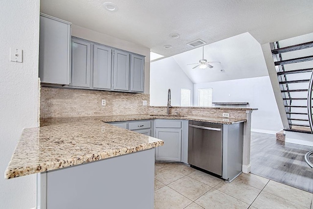 kitchen with stainless steel dishwasher, kitchen peninsula, sink, and vaulted ceiling