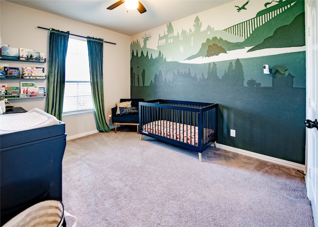 bedroom with a nursery area, carpet floors, and ceiling fan