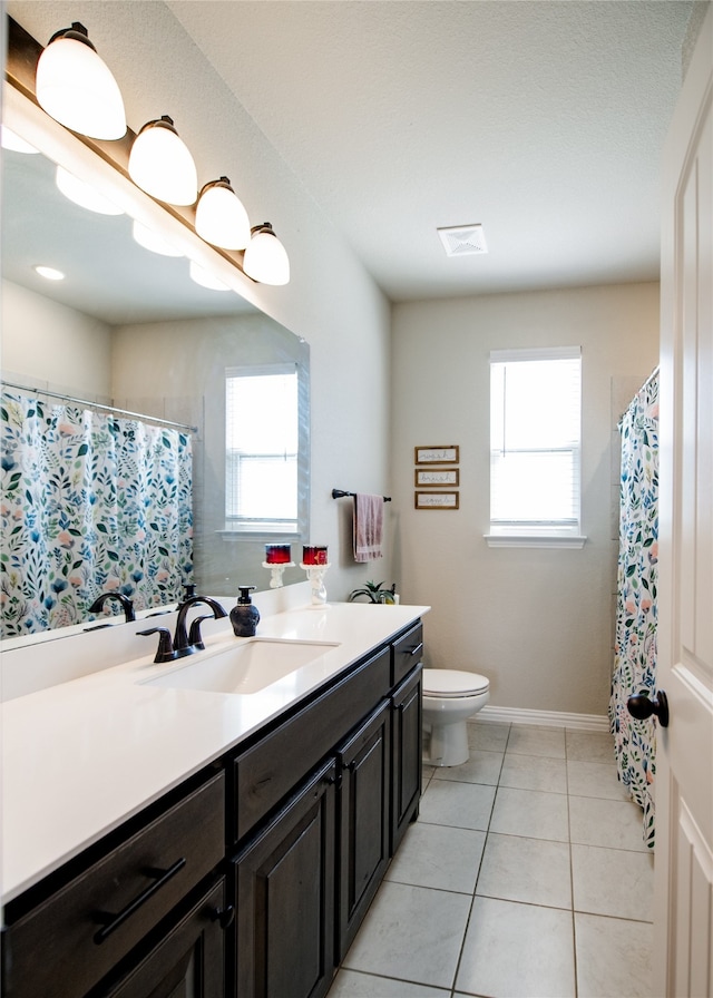 bathroom with vanity, toilet, tile patterned floors, and a wealth of natural light