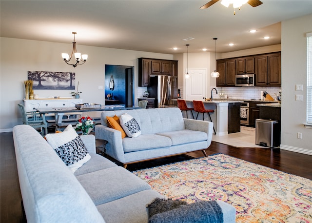 living room featuring light hardwood / wood-style floors, sink, and ceiling fan with notable chandelier