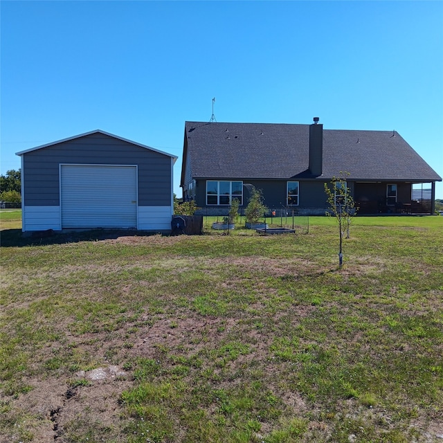 rear view of house featuring a yard, an outbuilding, and a garage