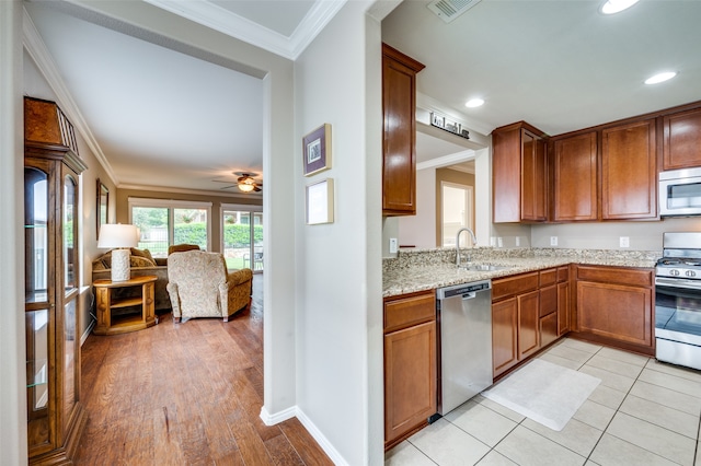 kitchen with ceiling fan, sink, ornamental molding, light hardwood / wood-style flooring, and appliances with stainless steel finishes