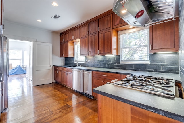 kitchen featuring appliances with stainless steel finishes, dark hardwood / wood-style flooring, tasteful backsplash, island range hood, and crown molding