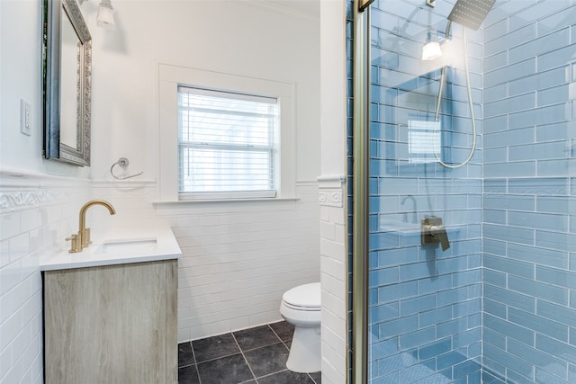 bathroom with tile patterned flooring, vanity, an enclosed shower, and tile walls