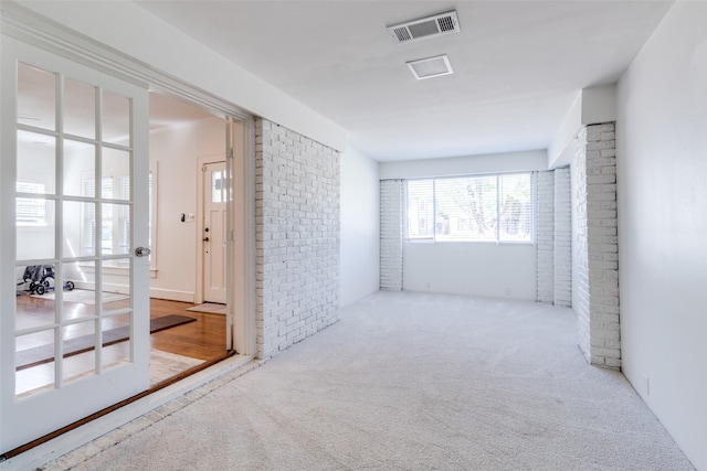 interior space featuring light colored carpet and brick wall