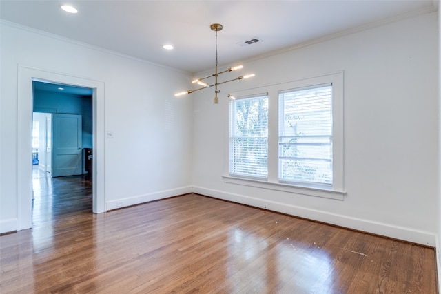 empty room with hardwood / wood-style floors, ornamental molding, and a notable chandelier